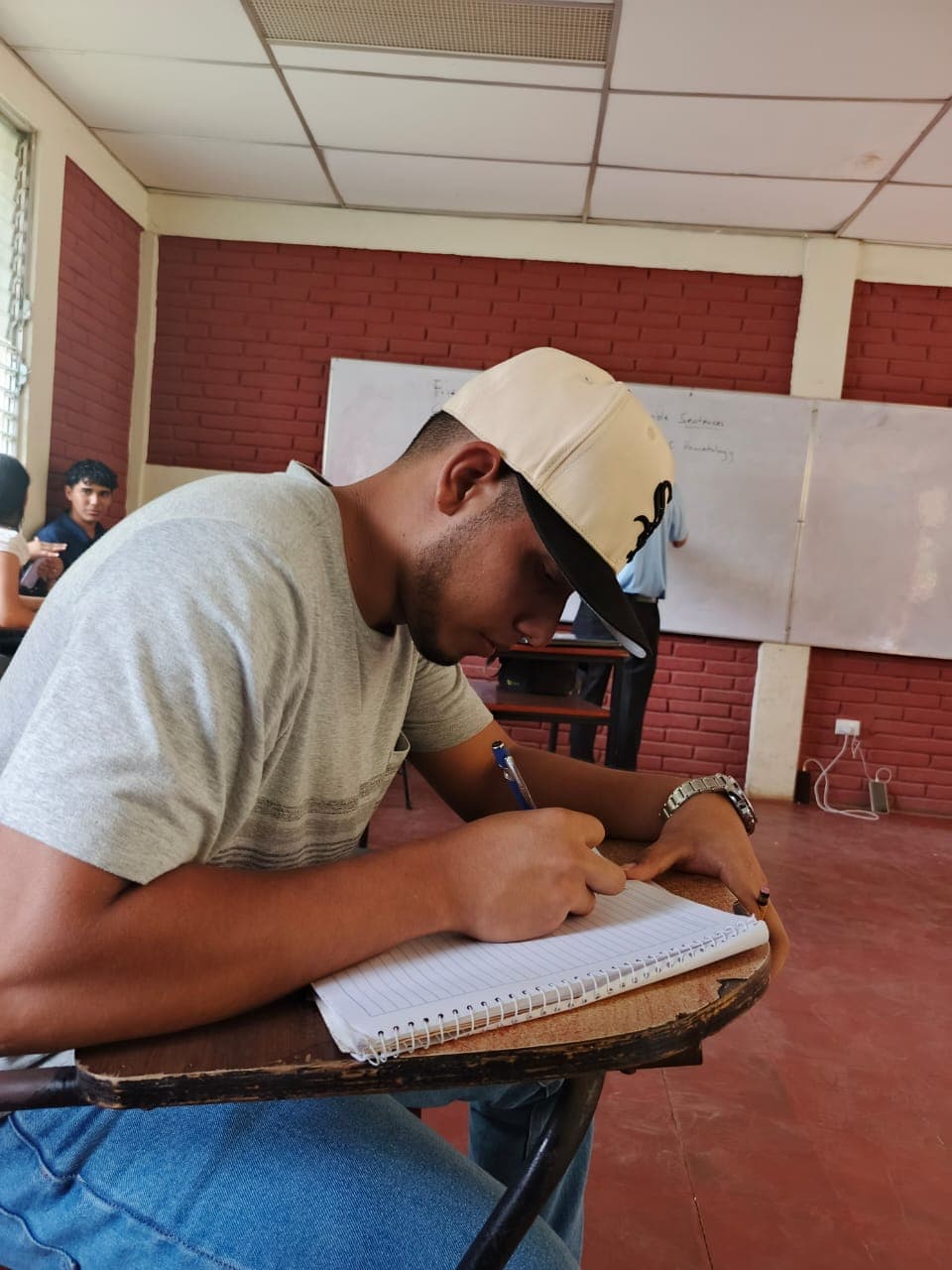 Milton, a scholarship recipient, studying at a classroom desk